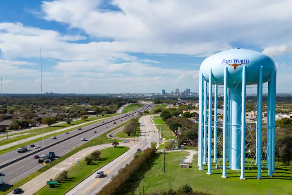 Aerial view of freeway and large blue water tower with Fort Worth logo on it in Fort Worth, Texas.